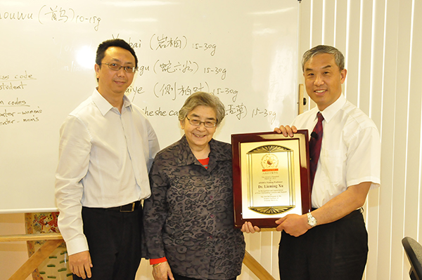 DAOM visiting professor holding placque with President Yen